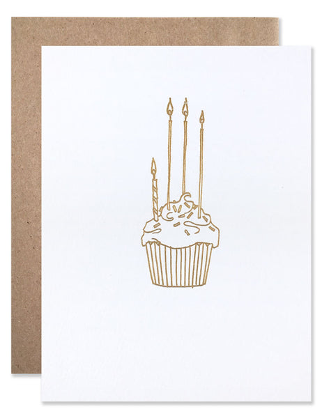 Gold foil cupcake with three tall candles and one short candle. Illustrated by Hartland Brooklyn.
